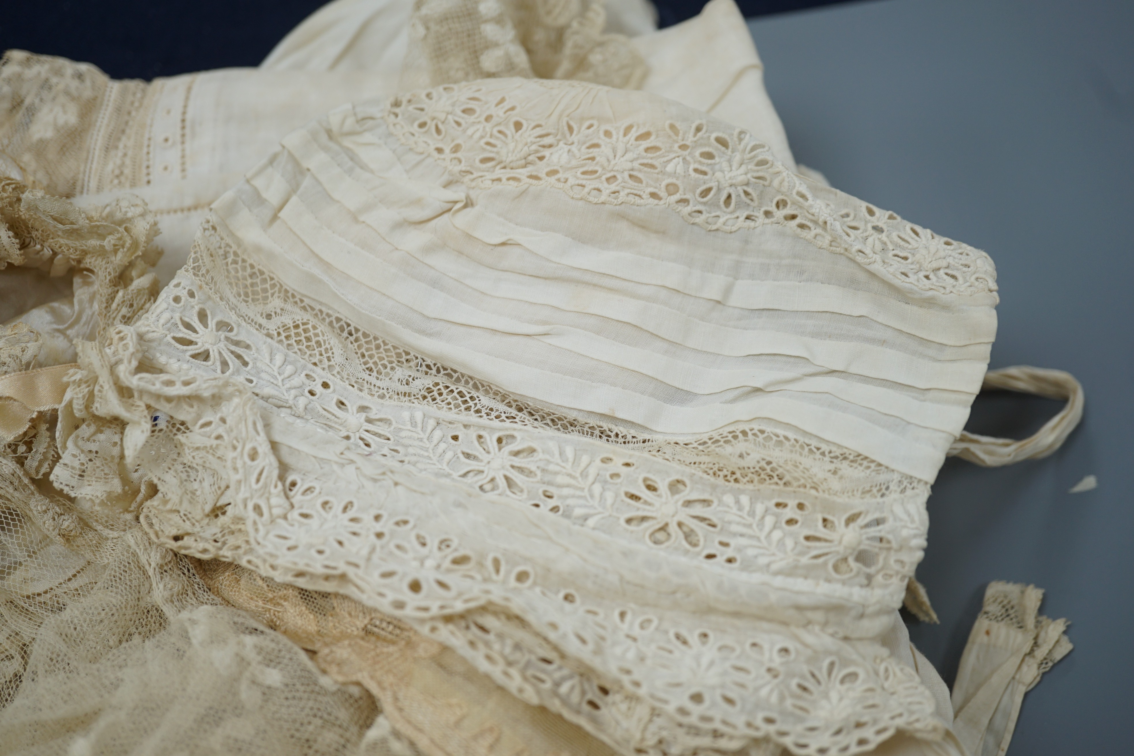 A collection of 19th century babywear, lace and cutwork bonnets and a christening bonnet and veil